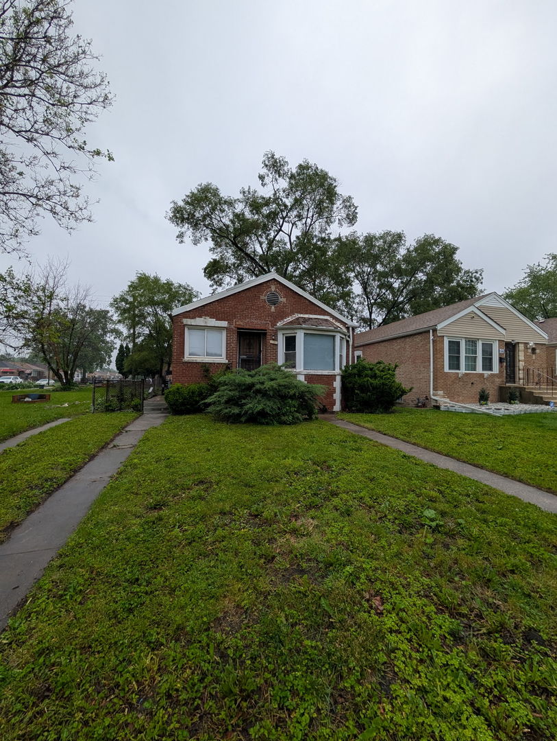 520 W 129th Pl, Chicago, IL 60628 - bungalow-style home featuring brick siding, a front lawn, a garage, and driveway