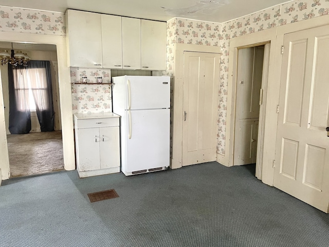 218 S Oneca St, Tonica, IL 61370 - kitchen featuring freestanding refrigerator, wallpapered walls, dark carpet, white cabinetry, and a chandelier