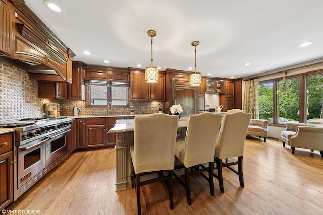 11522 Ridgewood Ln, Burr Ridge, IL 60527 - kitchen with double oven range, a kitchen breakfast bar, decorative backsplash, light wood-type flooring, and light stone countertops