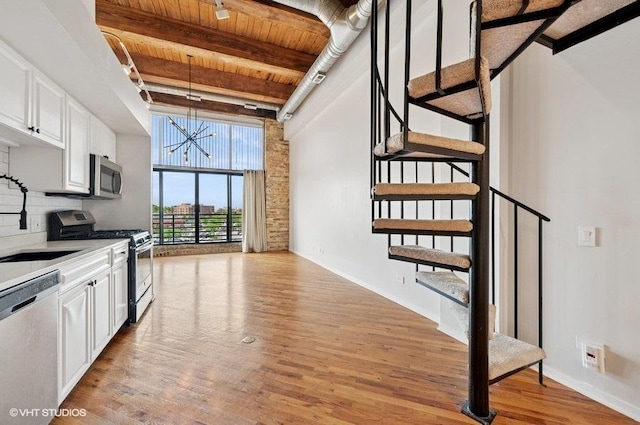 2614 N Clybourn Ave Unit 311, Chicago, IL 60614 - kitchen with appliances with stainless steel finishes, a wooden ceiling with exposed beams, a chandelier, light wood finished floors, and white cabinetry