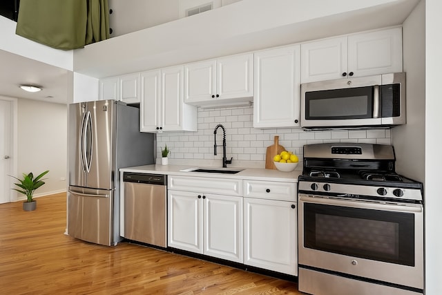 2614 N Clybourn Ave Unit 311, Chicago, IL 60614 - kitchen with appliances with stainless steel finishes, light countertops, light wood-style floors, and white cabinets