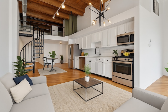 2614 N Clybourn Ave Unit 311, Chicago, IL 60614 - living room with rail lighting, a high ceiling, a wooden ceiling with exposed beams, stairway, and light wood finished floors
