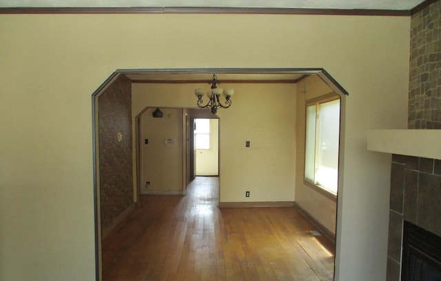 7319 S Claremont Ave, Chicago, IL 60636 - unfurnished dining area with hardwood / wood-style floors, a chandelier, a large fireplace, arched walkways, and ornamental molding