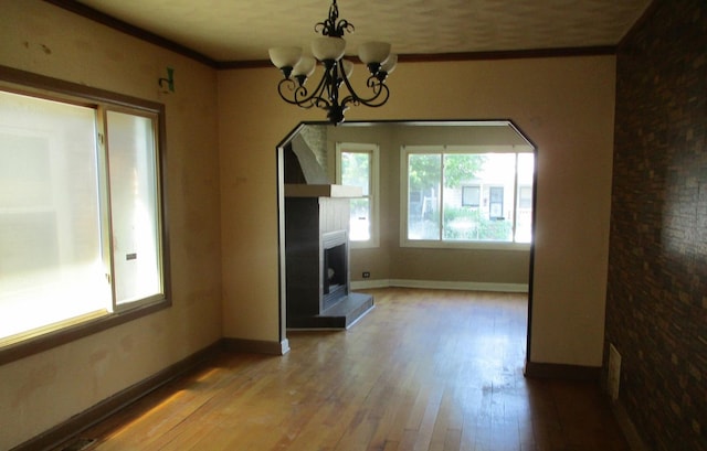 7319 S Claremont Ave, Chicago, IL 60636 - unfurnished dining area with hardwood / wood-style floors, a fireplace with raised hearth, a chandelier, and crown molding