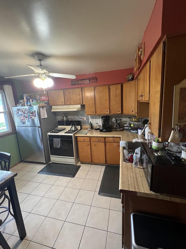 201 S Roy Ave, Northlake, IL 60164 - kitchen with freestanding refrigerator, white gas range oven, under cabinet range hood, brown cabinets, and a ceiling fan