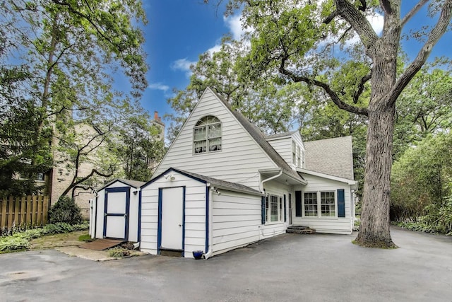 1667 Sunnyside Ave, Highland Park, IL 60035 - rear view of property featuring a storage unit, roof with shingles, and a patio
