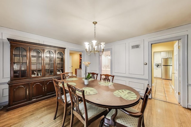 1667 Sunnyside Ave, Highland Park, IL 60035 - dining room featuring a decorative wall, a chandelier, and light wood-type flooring