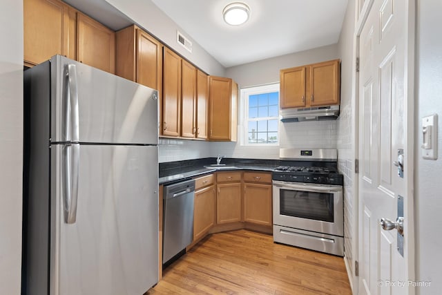 4321 N Drake Ave Unit 3W, Chicago, IL 60618 - kitchen featuring appliances with stainless steel finishes, under cabinet range hood, dark countertops, backsplash, and light wood-type flooring