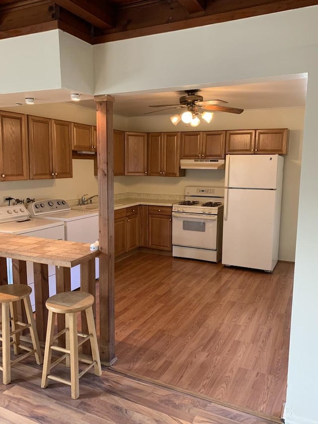 2605 Park St, Rolling Meadows, IL 60008 - kitchen with white appliances, under cabinet range hood, washing machine and dryer, light wood-style flooring, and brown cabinetry