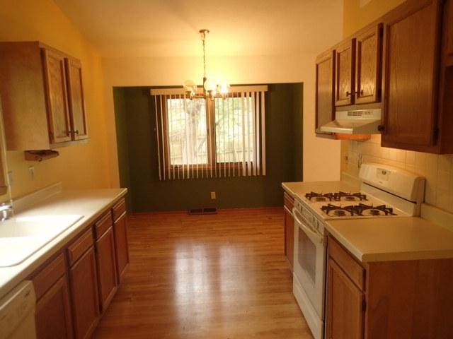 3430 Treadway Ct, Rockford, IL 61103 - kitchen featuring white appliances, under cabinet range hood, brown cabinetry, light wood finished floors, and a chandelier