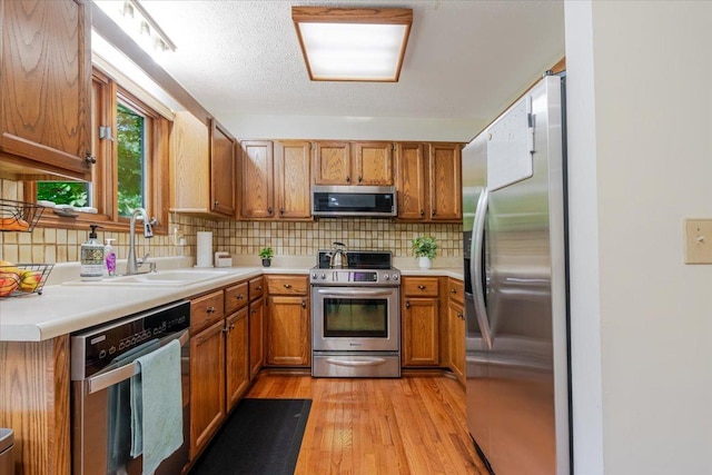 141 Manor Cir, Bloomington, IL 61704 - kitchen with stainless steel appliances, brown cabinets, light wood-type flooring, and backsplash
