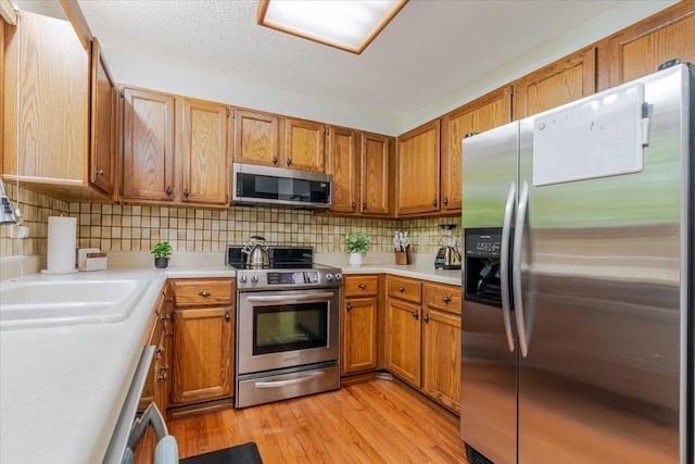 141 Manor Cir, Bloomington, IL 61704 - kitchen with appliances with stainless steel finishes, light countertops, decorative backsplash, and brown cabinetry