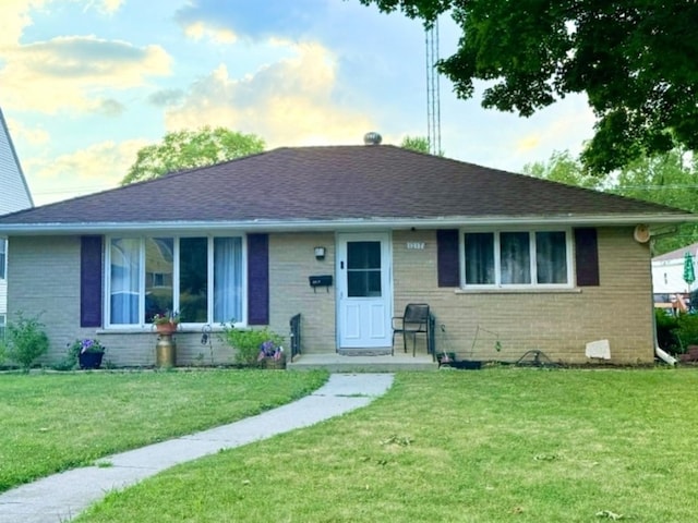 1217 S 7th Ave, Kankakee, IL 60901 - view of front of property with brick siding, a front yard, and a shingled roof