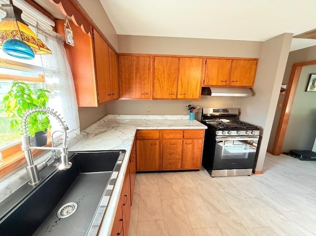 1217 S 7th Ave, Kankakee, IL 60901 - kitchen with stainless steel gas stove, under cabinet range hood, light countertops, and brown cabinetry
