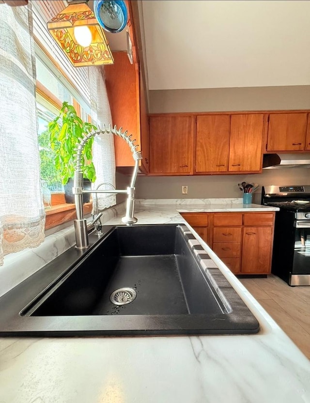 1217 S 7th Ave, Kankakee, IL 60901 - kitchen featuring gas stove, brown cabinets, under cabinet range hood, and light countertops