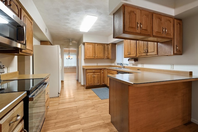 1405 1st Ave, Sterling, IL 61081 - kitchen featuring appliances with stainless steel finishes, brown cabinets, ceiling fan, a peninsula, and light wood finished floors