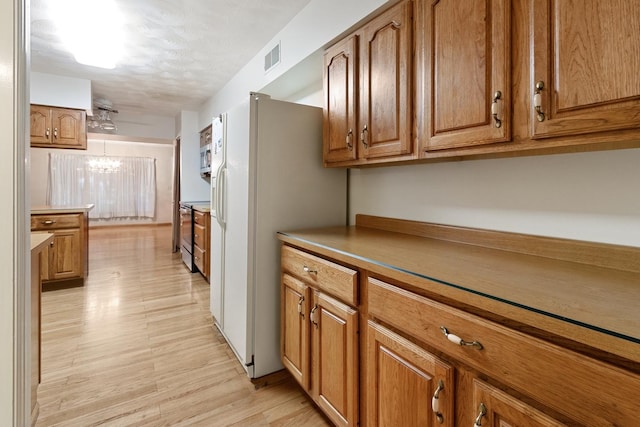 1405 1st Ave, Sterling, IL 61081 - kitchen featuring brown cabinetry, white refrigerator with ice dispenser, light wood-type flooring, a chandelier, and a textured ceiling