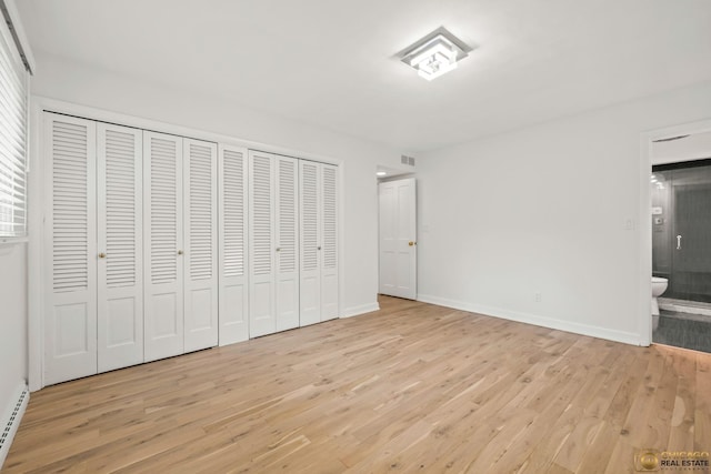 8019 S Malta Rd, Dekalb, IL 60115 - unfurnished bedroom with light wood-style floors, multiple closets, ensuite bath, and a baseboard radiator