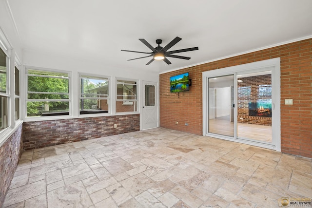 8019 S Malta Rd, Dekalb, IL 60115 - unfurnished sunroom featuring a ceiling fan, brick wall, and stone tile floors