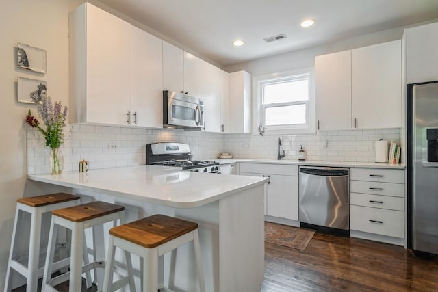 2144 W Schiller St Unit H, Chicago, IL 60622 - kitchen featuring appliances with stainless steel finishes, light countertops, a peninsula, dark wood-type flooring, and a kitchen bar