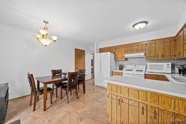13301 Maverick Trl, Homer Glen, IL 60491 - kitchen featuring white appliances, under cabinet range hood, a chandelier, decorative backsplash, and light countertops