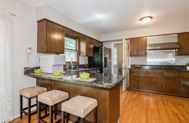 200 Timbercrest Dr, Schaumburg, IL 60193 - kitchen with wall chimney range hood, stainless steel fridge with ice dispenser, a peninsula, light wood finished floors, and a kitchen breakfast bar