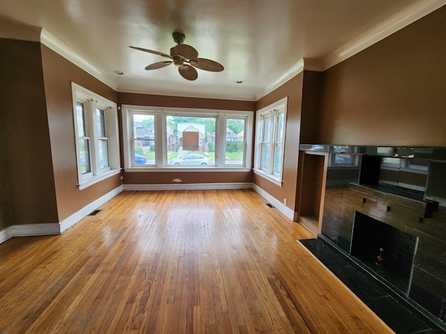 7542 S Prairie Ave, Chicago, IL 60619 - unfurnished living room featuring a ceiling fan, wood-type flooring, crown molding, and a tiled fireplace
