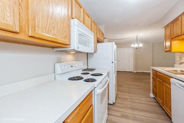 509 Aurora Ave Unit 409, Naperville, IL 60540 - kitchen featuring white appliances, light countertops, light wood-type flooring, decorative light fixtures, and a chandelier