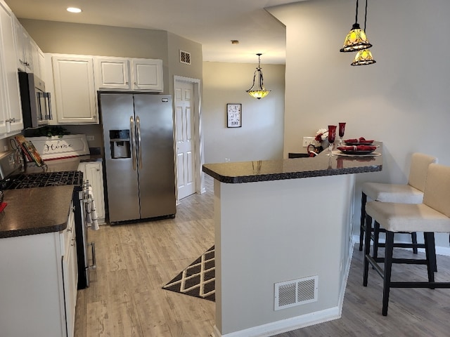 2949 Brossman St, Naperville, IL 60564 - kitchen featuring appliances with stainless steel finishes, dark countertops, light wood finished floors, a peninsula, and white cabinets
