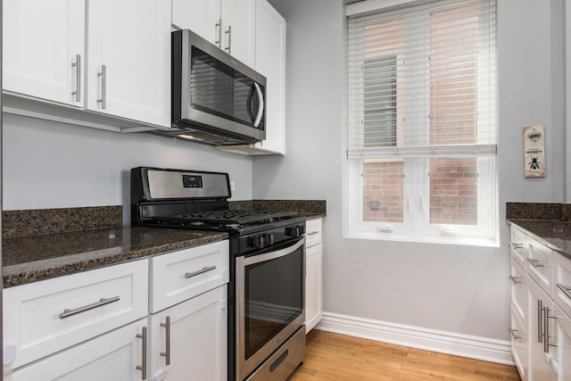 2409 W Catalpa Ave Unit 307, Chicago, IL 60625 - kitchen featuring appliances with stainless steel finishes, white cabinets, dark stone countertops, and light wood-style flooring
