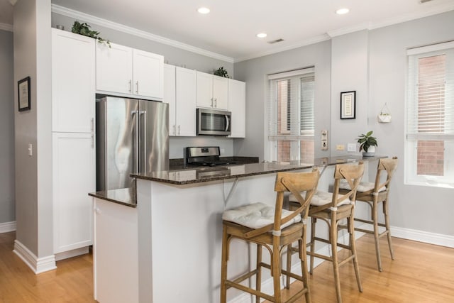 2409 W Catalpa Ave Unit 307, Chicago, IL 60625 - kitchen featuring stainless steel appliances, light wood-style floors, a breakfast bar, recessed lighting, and dark stone countertops