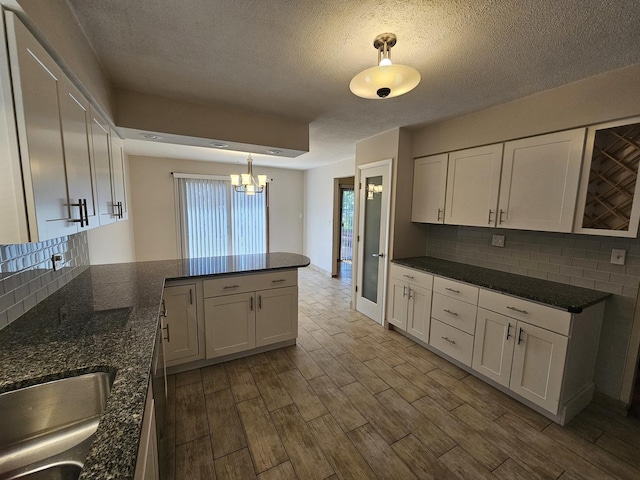7215 Beckwith Rd, Morton Grove, IL 60053 - kitchen featuring white cabinets, a chandelier, backsplash, dark wood-type flooring, and a textured ceiling