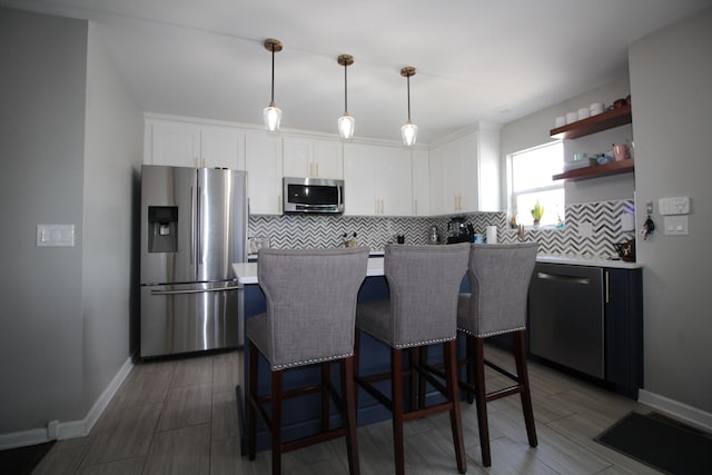 6142 W 60th St, Chicago, IL 60638 - kitchen featuring appliances with stainless steel finishes, decorative backsplash, white cabinets, a kitchen island, and a breakfast bar area