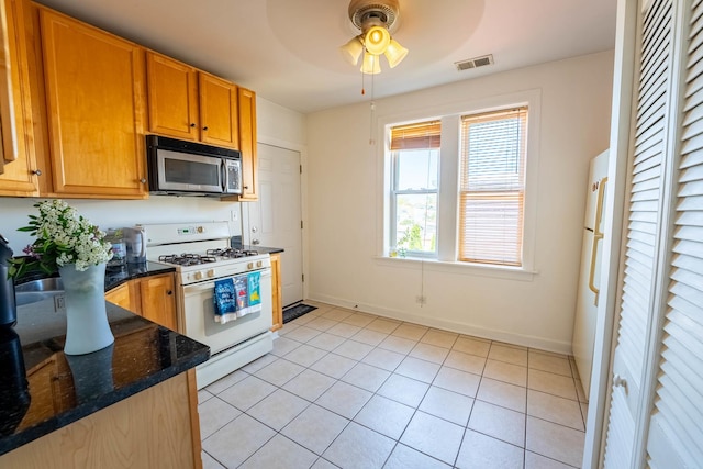3043 N Laramie Ave Unit 2, Chicago, IL 60641 - kitchen with stainless steel microwave, white range with gas cooktop, a ceiling fan, light tile patterned floors, and dark stone counters