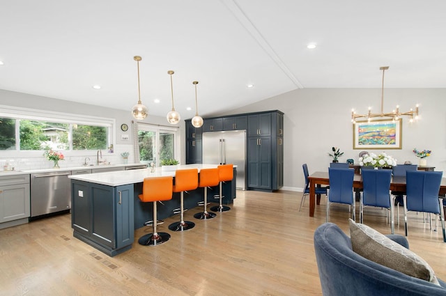 9050 Tamaroa Ter, Skokie, IL 60076 - kitchen with appliances with stainless steel finishes, a chandelier, light countertops, a breakfast bar, and light wood finished floors