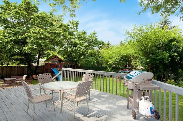 9050 Tamaroa Ter, Skokie, IL 60076 - deck with a grill, outdoor dining area, a playground, and view of wooded area