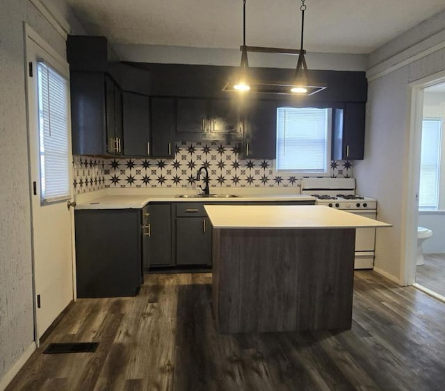 207 W Main St, La Harpe, IL 61450 - kitchen featuring white range with gas stovetop, dark wood finished floors, light countertops, a kitchen island, and decorative backsplash