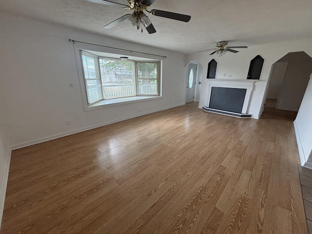 3667 Arthesia St E, Armstrong, IL 61812 - unfurnished living room with a ceiling fan, arched walkways, wood finished floors, and a fireplace