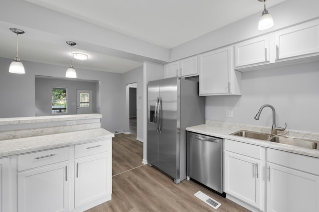 541 N May St, Aurora, IL 60506 - kitchen featuring appliances with stainless steel finishes, light wood-type flooring, white cabinetry, and decorative light fixtures