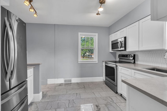 193 May St, Bensenville, IL 60106 - kitchen featuring stainless steel appliances, rail lighting, white cabinets, and decorative backsplash