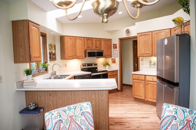 2107 10th Ave, Sterling, IL 61081 - kitchen with appliances with stainless steel finishes, light wood finished floors, a peninsula, light countertops, and a chandelier