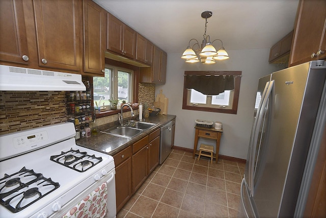 1411 E Hickory St, Streator, IL 61364 - kitchen featuring stainless steel appliances, a chandelier, under cabinet range hood, dark countertops, and decorative backsplash