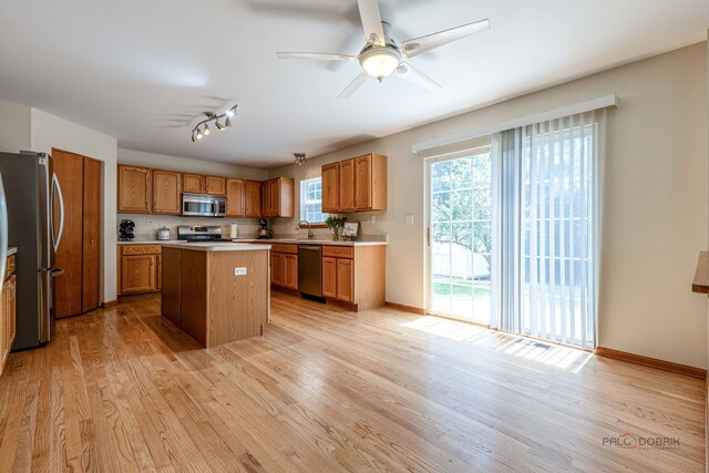 330 Greenview Ln, Lake Villa, IL 60046 - kitchen featuring appliances with stainless steel finishes, light wood-style flooring, light countertops, a kitchen island, and brown cabinets