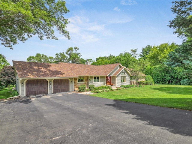 12828 Menominee Trl, Roscoe, IL 61073 - view of front of house featuring a garage, asphalt driveway, a front yard, and a chimney