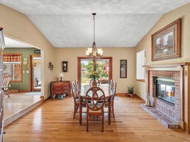 12828 Menominee Trl, Roscoe, IL 61073 - dining area with vaulted ceiling, a chandelier, light wood-type flooring, and a fireplace