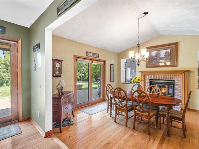 12828 Menominee Trl, Roscoe, IL 61073 - dining room featuring light wood finished floors, a chandelier, lofted ceiling, healthy amount of natural light, and a brick fireplace
