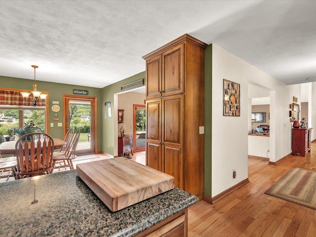 12828 Menominee Trl, Roscoe, IL 61073 - kitchen with light wood-style floors, dark countertops, a chandelier, brown cabinetry, and pendant lighting