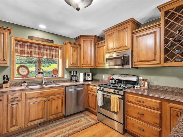 12828 Menominee Trl, Roscoe, IL 61073 - kitchen with appliances with stainless steel finishes, light wood-style floors, brown cabinetry, dark stone counters, and recessed lighting