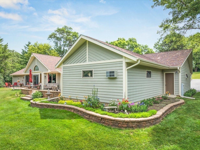 12828 Menominee Trl, Roscoe, IL 61073 - view of property exterior with a yard, a shingled roof, a patio, and an AC wall unit