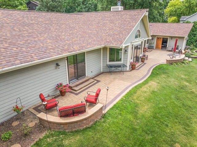 12828 Menominee Trl, Roscoe, IL 61073 - rear view of house with a patio area, a shingled roof, a lawn, and a fire pit